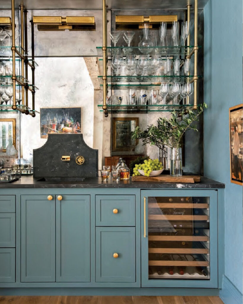 Luxe Interiors + Design Houston - Starting Fresh - Sherwin-Williams Riverway brightens the bar area with its custom cabinetry, brass-and-glass shelves fabricated by Peck & Company and a metallic raffia wallcovering by Donghia.