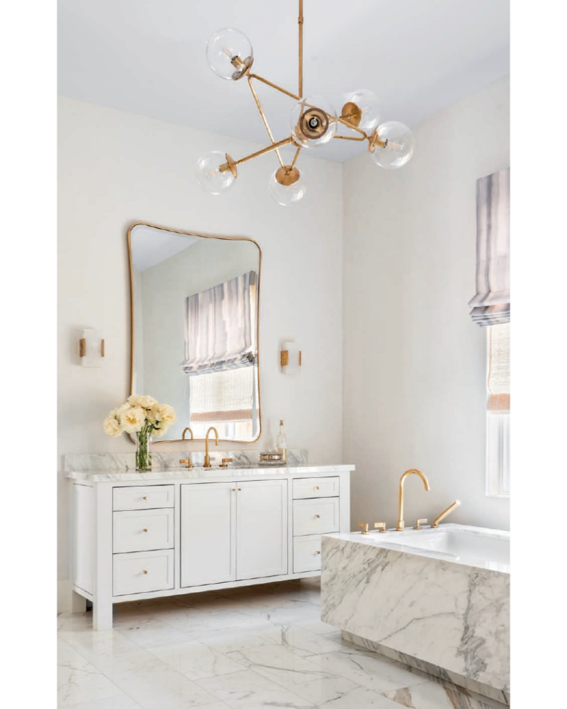 Luxe Interiors + Design Houston - Starting Fresh - The main bathroom’s Calacatta Extra tub surround and countertops from Walker Zanger and Calacatta Daniele flooring from Ann Sacks blend with plastered walls in Sherwin-Williams Whitetail. The chandelier from Circa Lighting adds glamour.